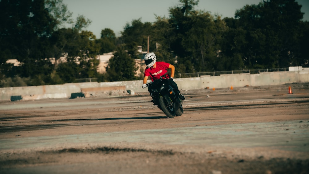 uomo in tuta da motociclista rossa e nera che guida su una motocicletta rossa e bianca durante il giorno