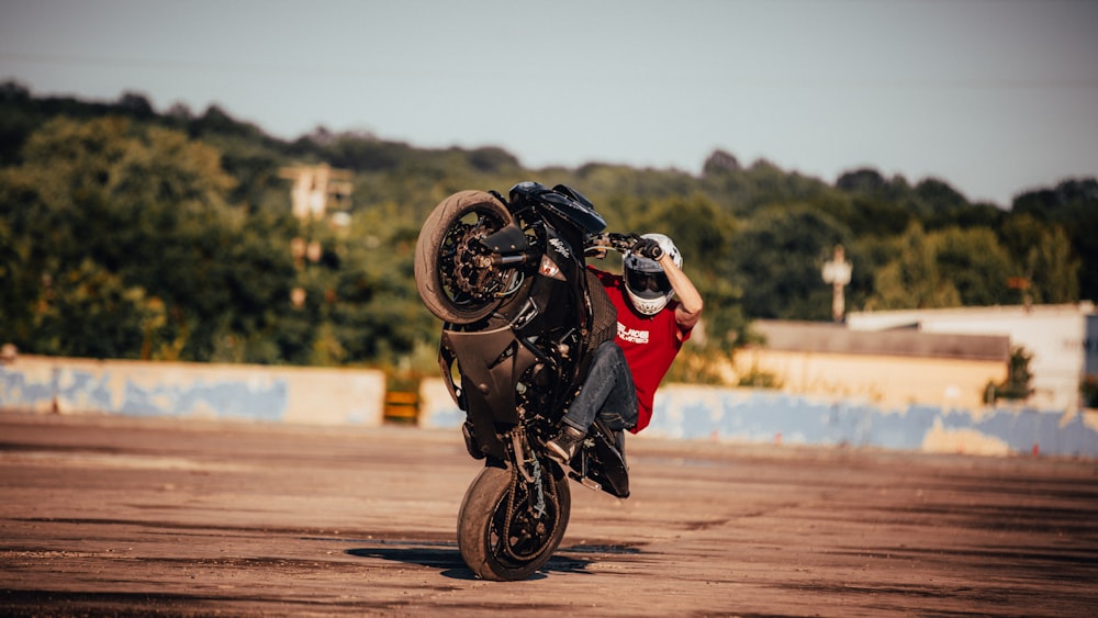 homme en chemise rouge conduisant une moto sur la route pendant la journée