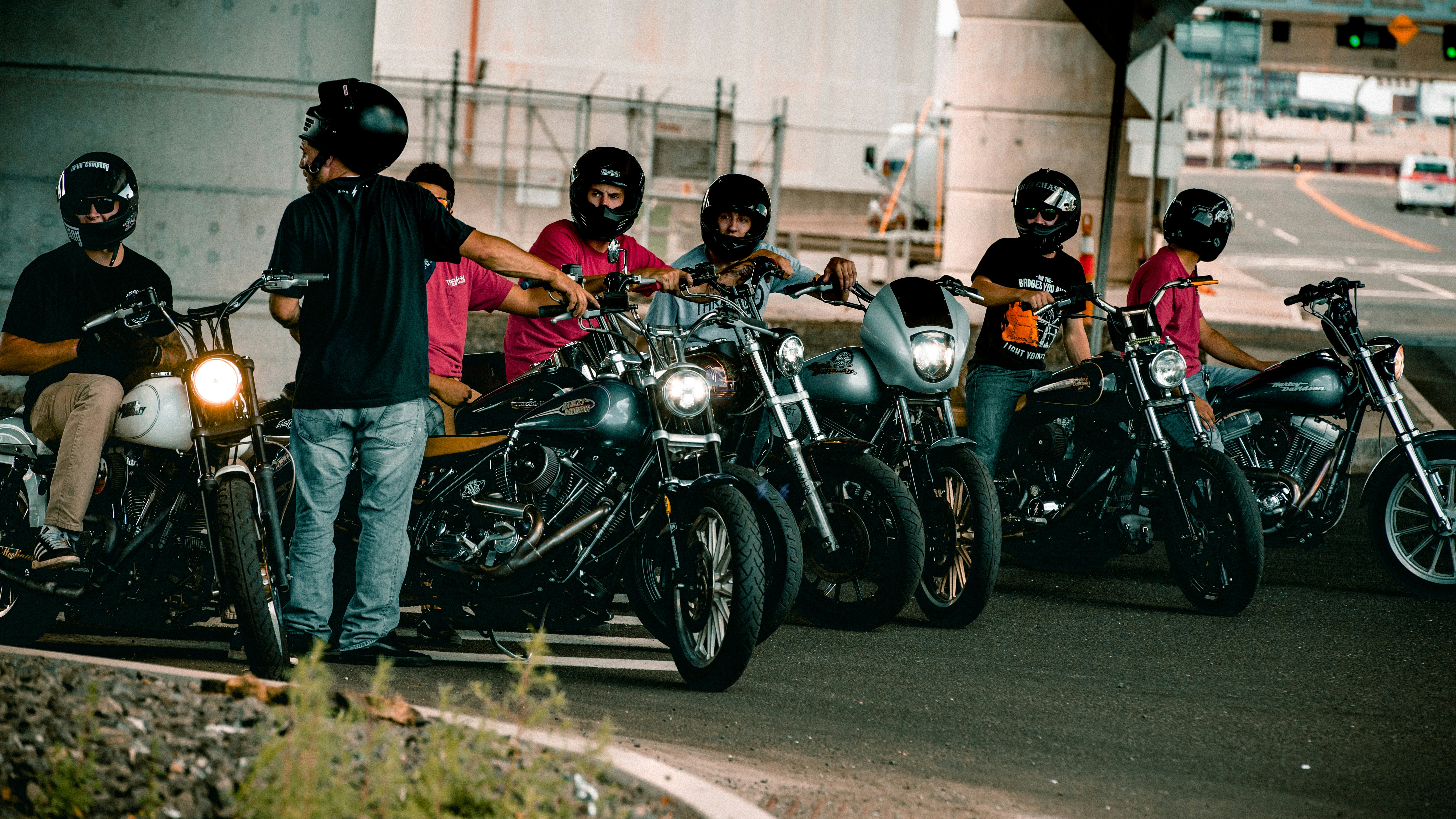 man in blue t-shirt and blue denim jeans standing beside black cruiser motorcycle
