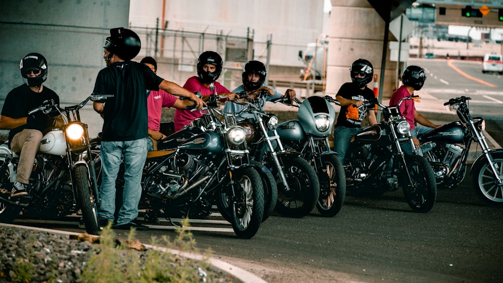 man in blue t-shirt and blue denim jeans standing beside black cruiser motorcycle