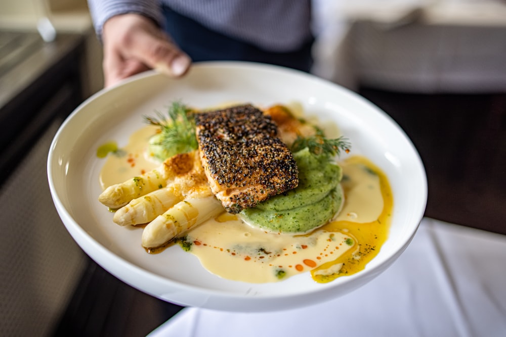 Person, die weiße Keramikplatte mit Essen hält