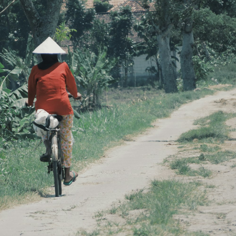 man in orange shirt riding bicycle on road during daytime