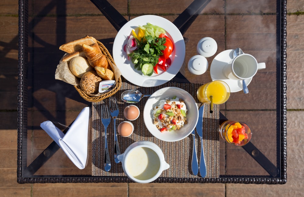 vegetable salad on white ceramic bowl beside bread on table