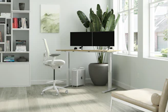 A sleek modern office desk with a comfortable ergonomic chair bathed in natural light.