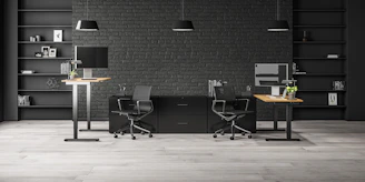 A sleek adjustable height office desk in a bright, modern workspace with natural light.