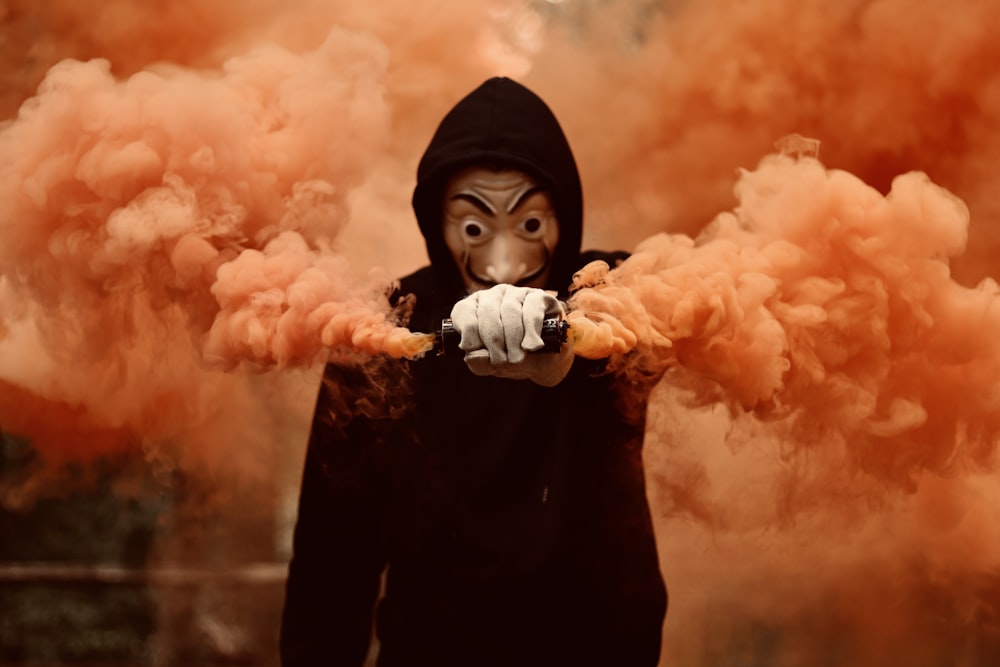 girl in black hoodie holding orange smoke