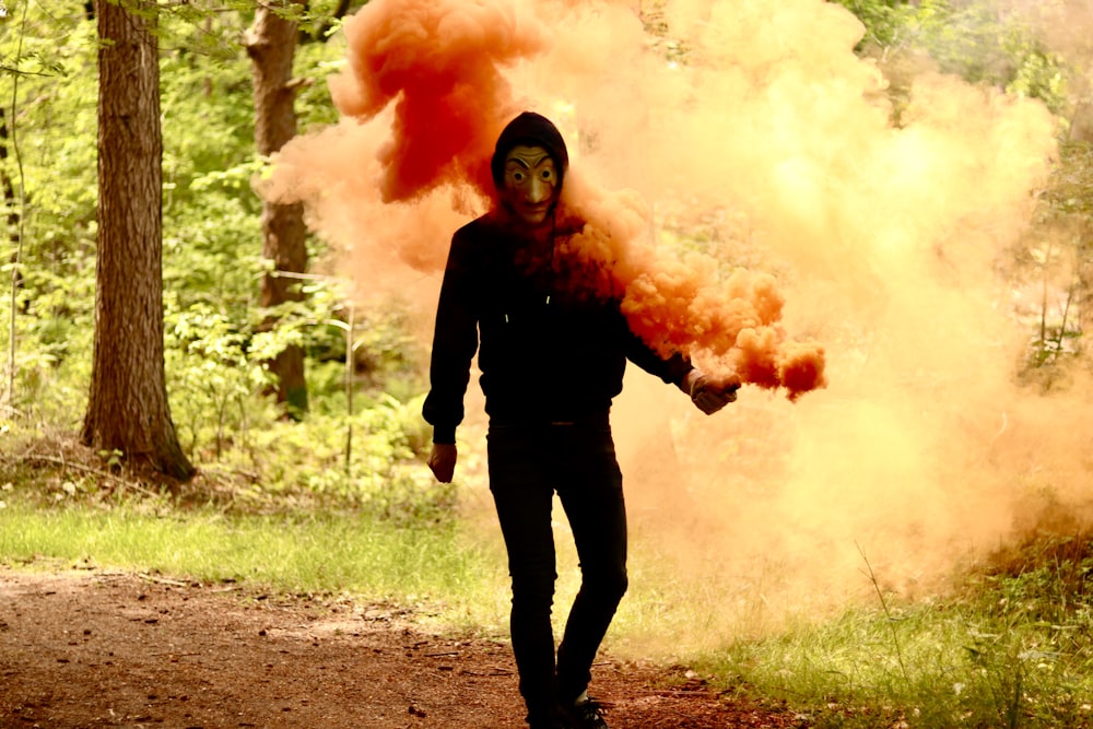 woman in black long sleeve shirt holding orange smoke