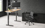 Adjustable height office desk in a bright, modern home office setting.