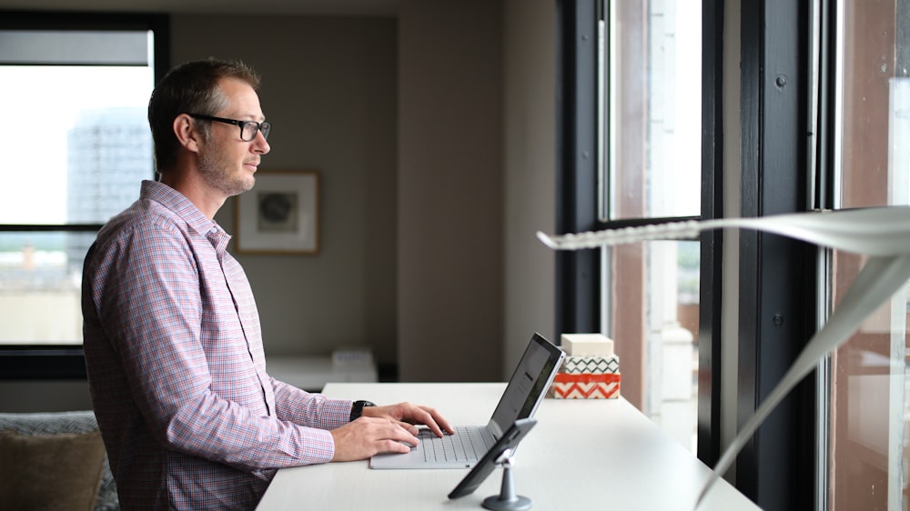 man in purple dress shirt using laptop computer