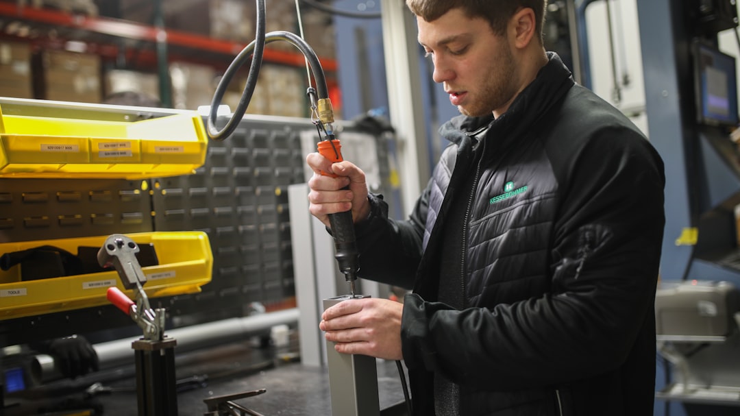 man in black jacket holding black and yellow hand tool