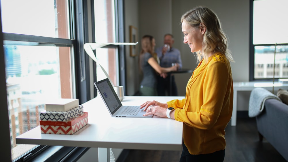 a woman in a yellow shirt is using a laptop