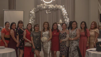 Elegant gathering of women in soft pink and black attire, smiling and enjoying a warm ambiance.