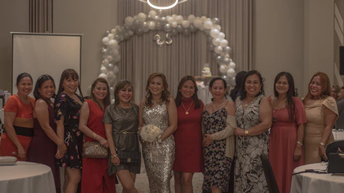 A group of women laughing together in chic black and gold outfits from Mevara.