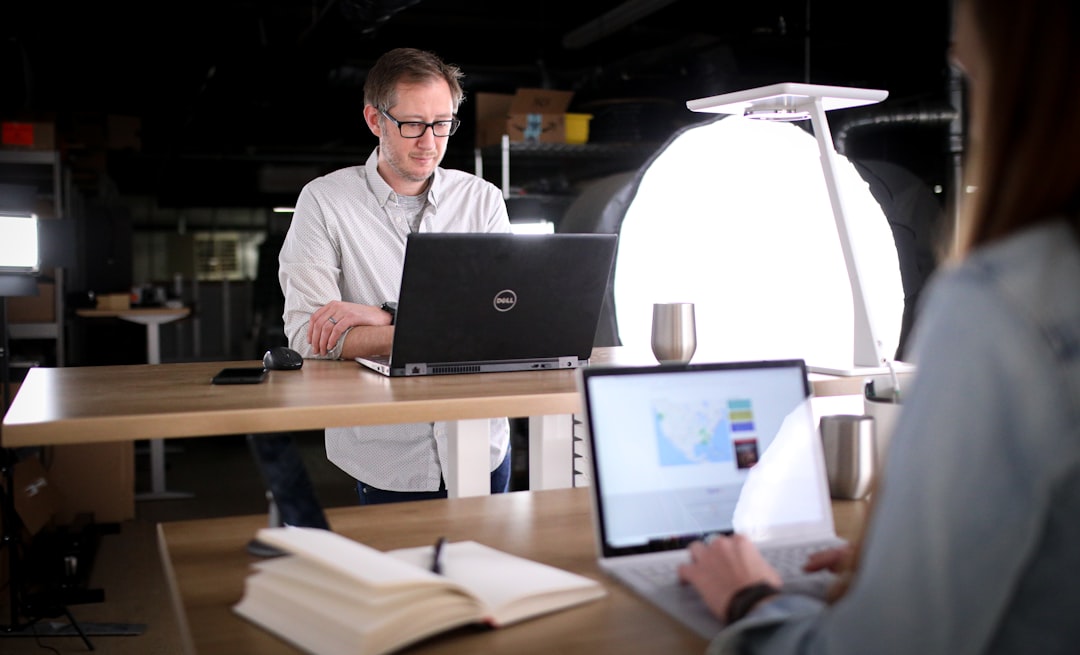 man in white dress shirt sitting in front of macbook