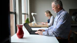 man in blue and white plaid dress shirt using macbook pro