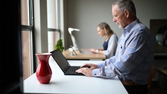 A person working intently on a laptop in an office.