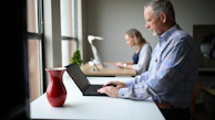 man in blue and white plaid dress shirt using macbook pro