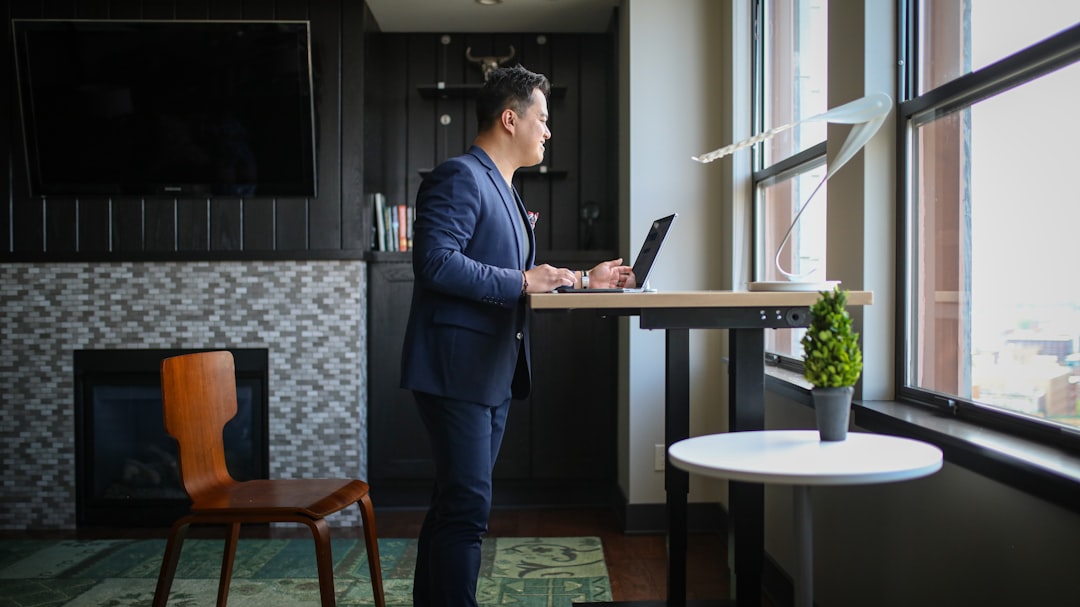 man in blue dress shirt and blue pants standing beside table