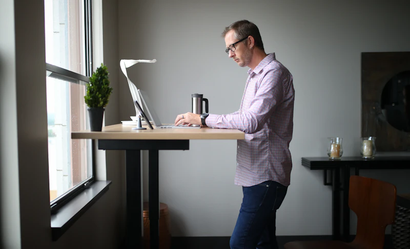 Patient standing upright at a standing desk with corrected posture after spinal alignment treatment