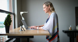 woman in white robe sitting on chair using laptop computer