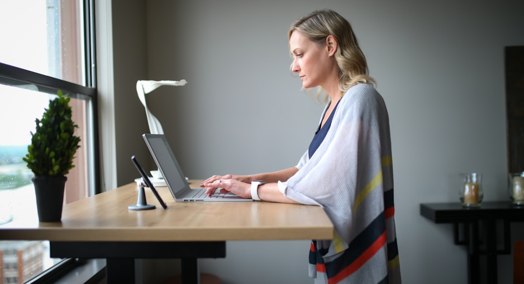 woman in white robe sitting on chair using laptop computer