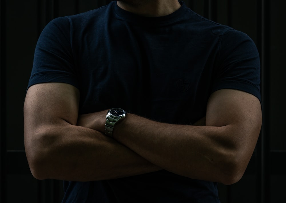 a man with his arms crossed wearing a watch