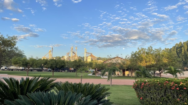 A lush green landscape with a Birla factory in the background under clear blue skies, symbolizing harmony between industry and nature.