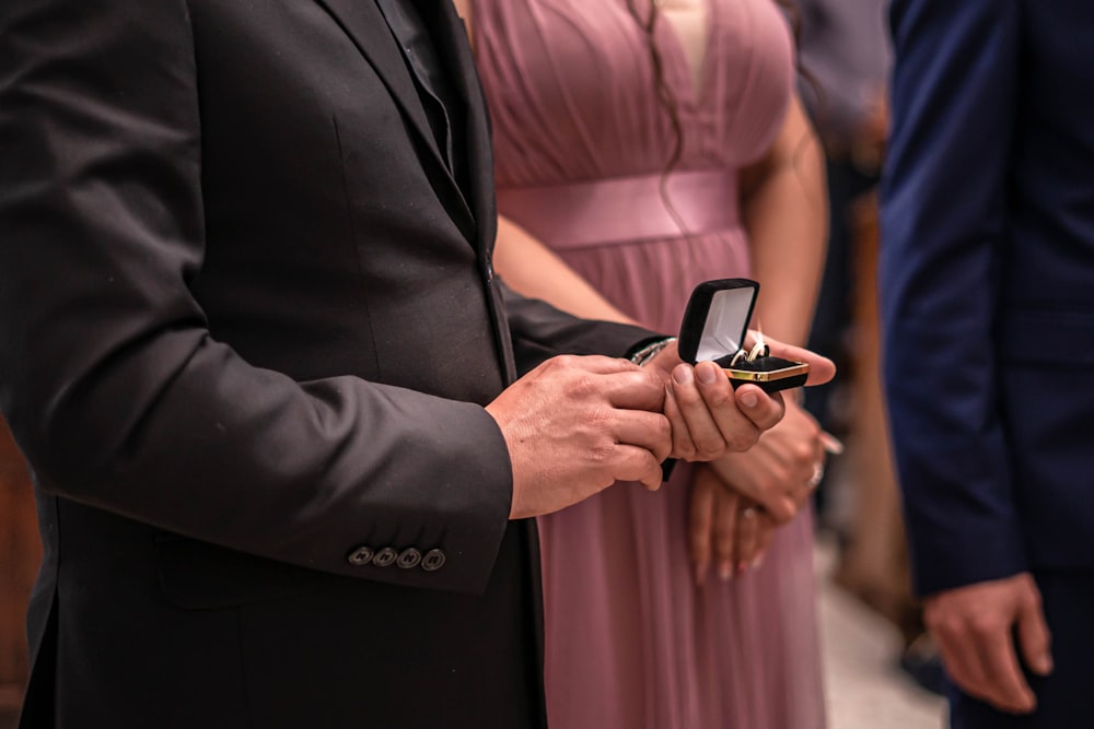 man in black suit holding black smartphone