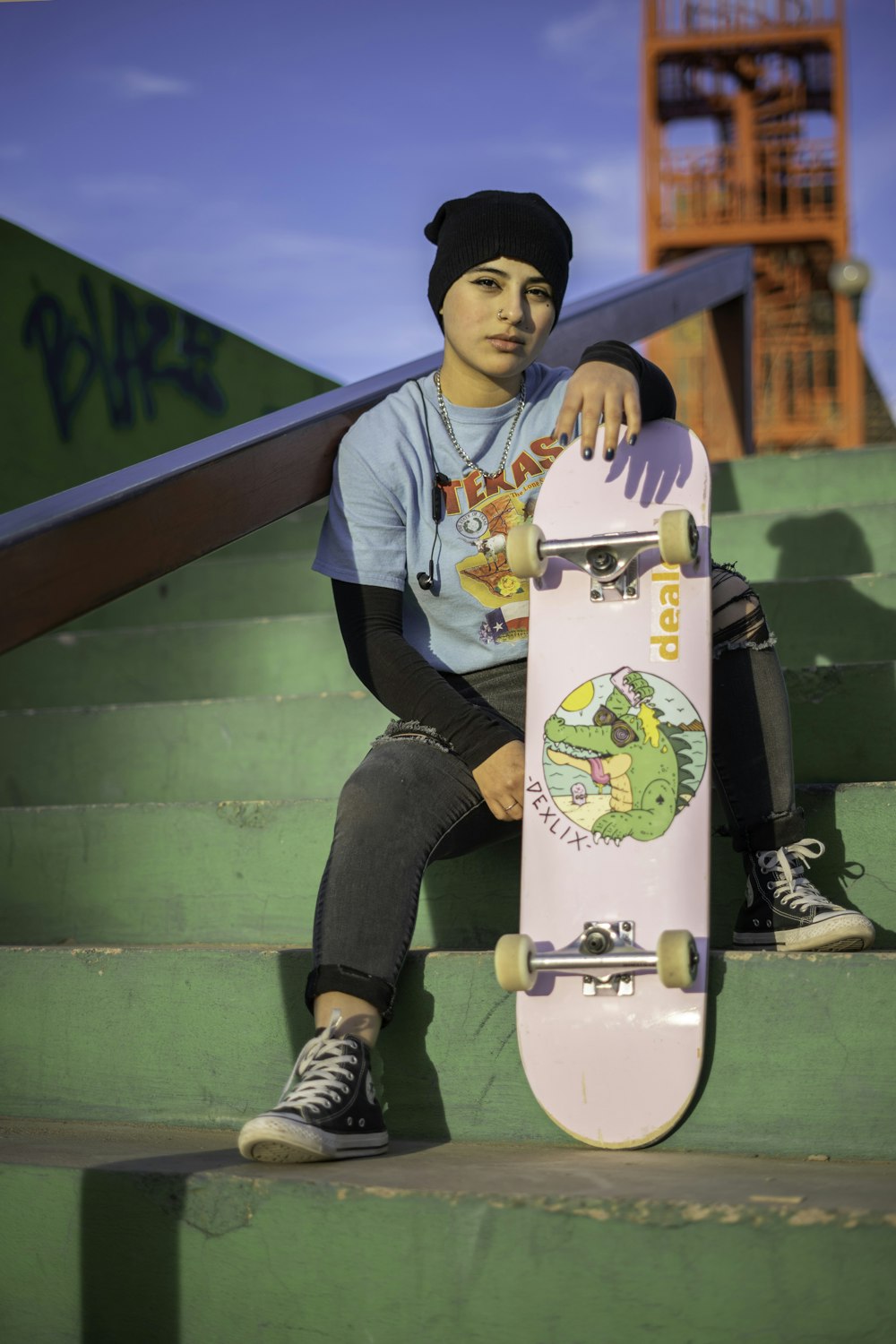 man in white crew neck t-shirt and black pants sitting on yellow skateboard during daytime