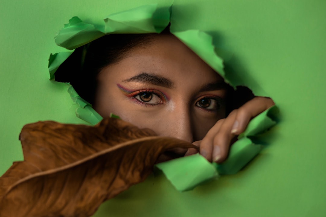 woman covering her face with green leaf