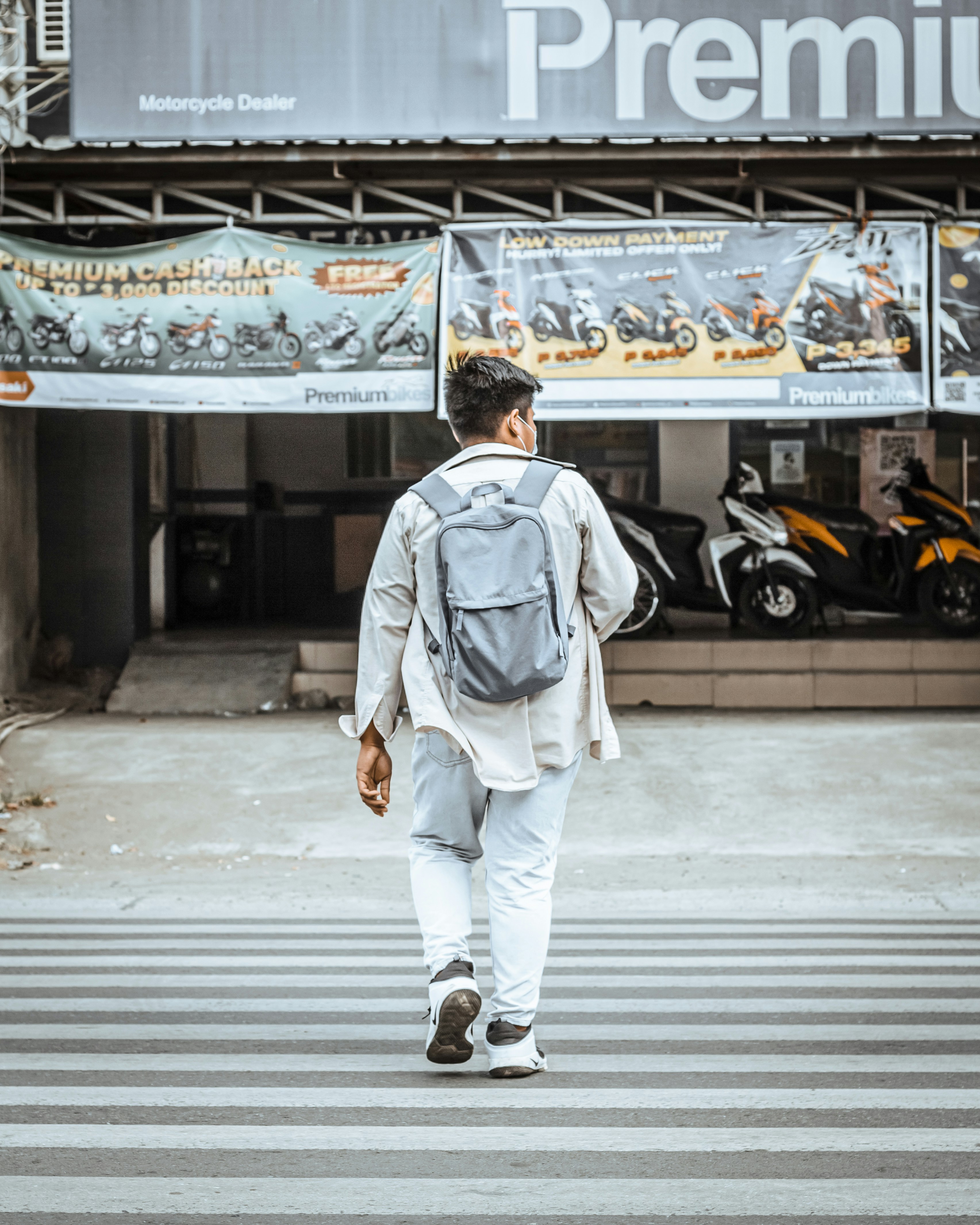 man in white jacket walking on pedestrian lane during daytime