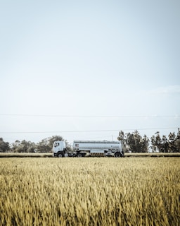 A water tanker parked beside a farm field, ready to irrigate crops.