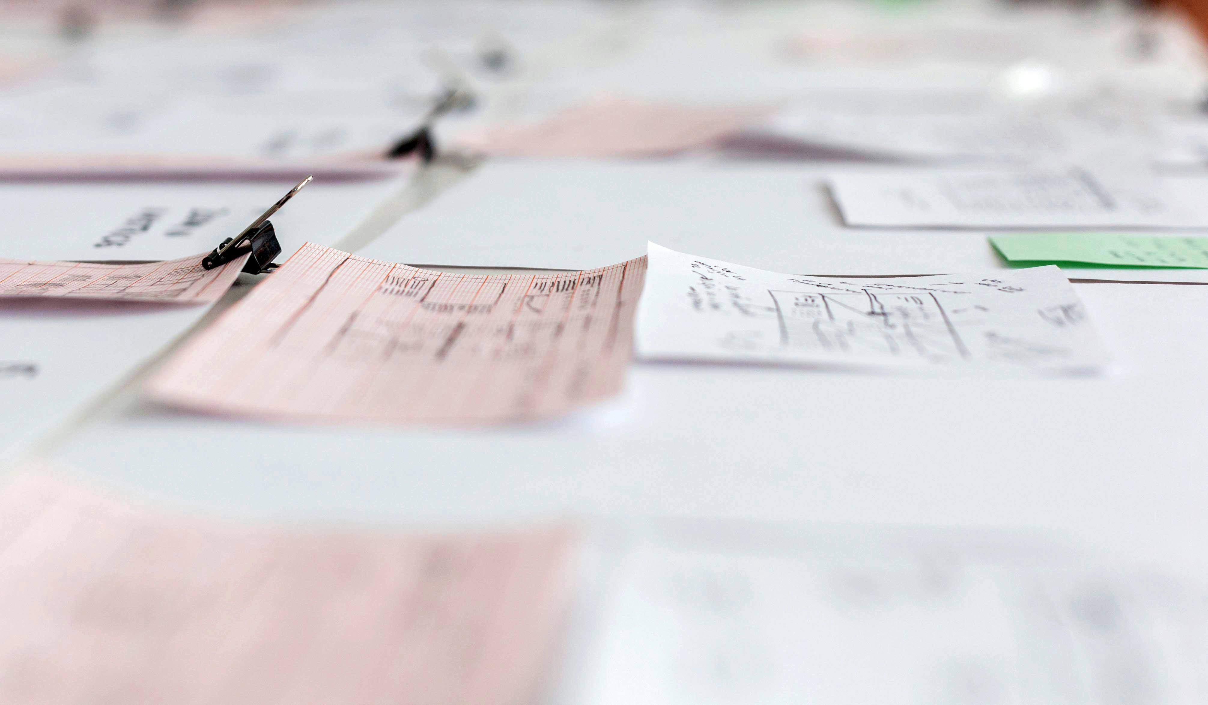 Policy documents and research papers spread on a desk with charts showing student debt relief proposals and implementation timelines
