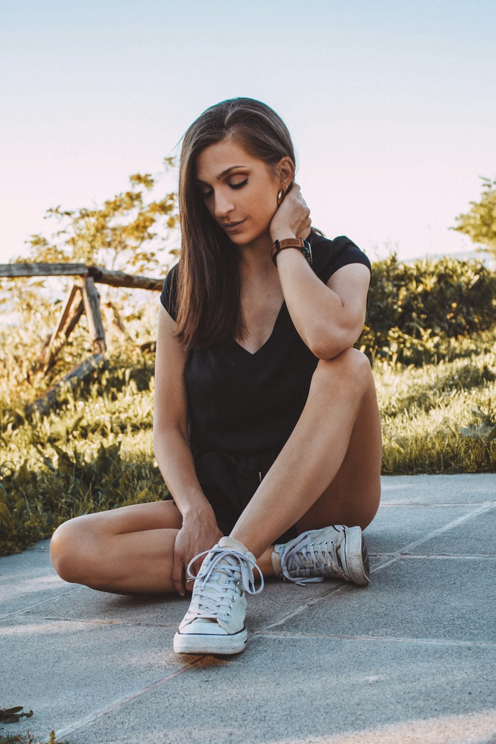 woman in black tank top and blue denim jeans sitting on gray concrete floor during daytime