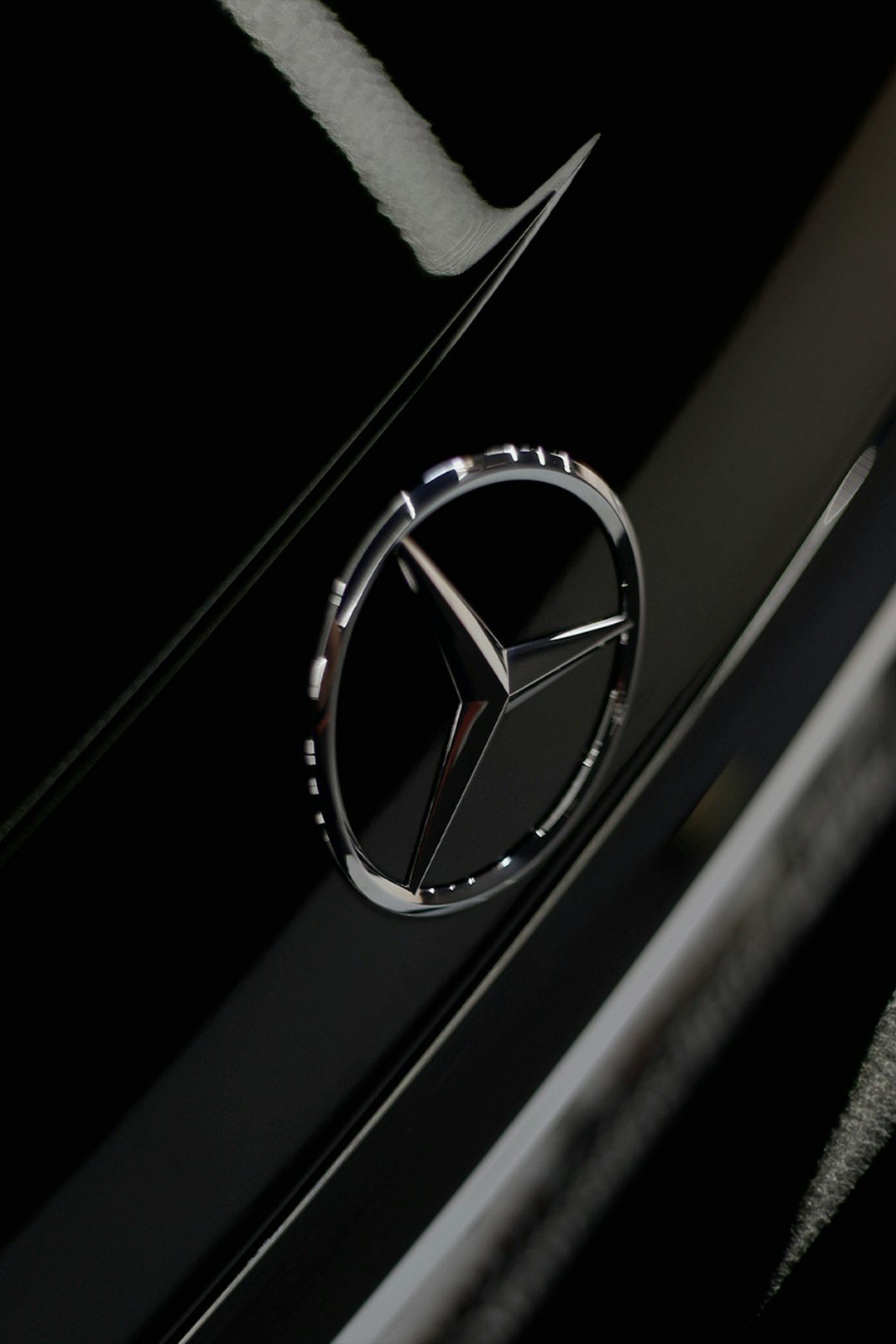 silver mercedes benz emblem on black surface