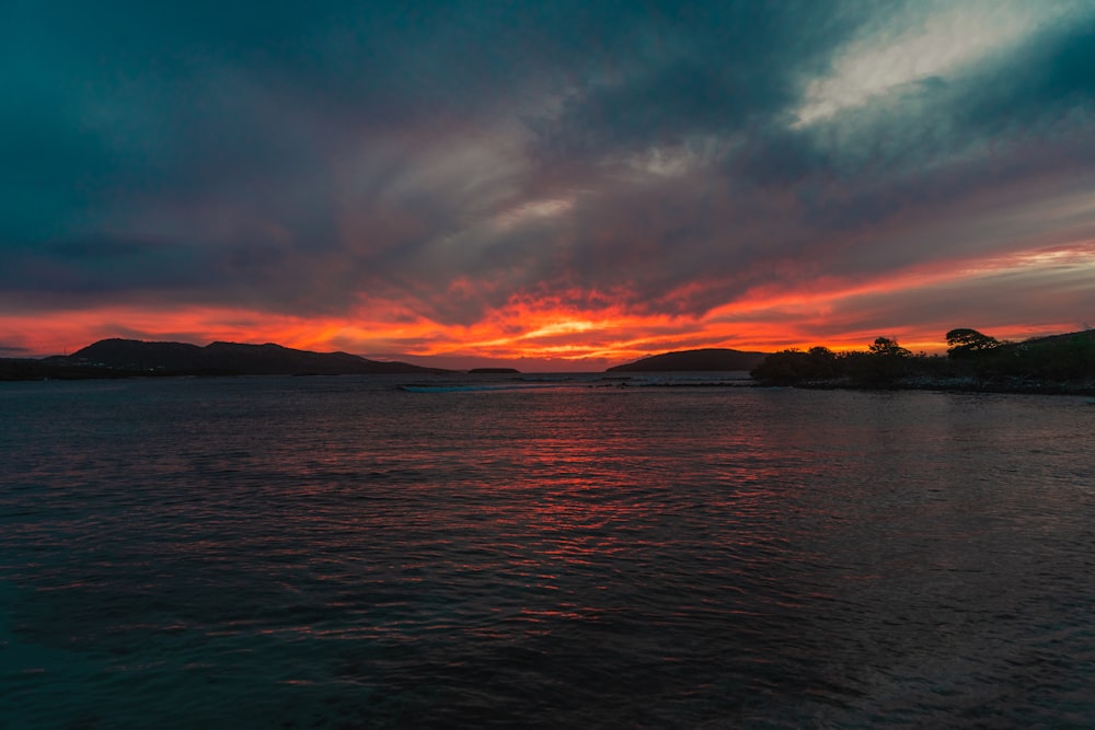 body of water under cloudy sky during sunset