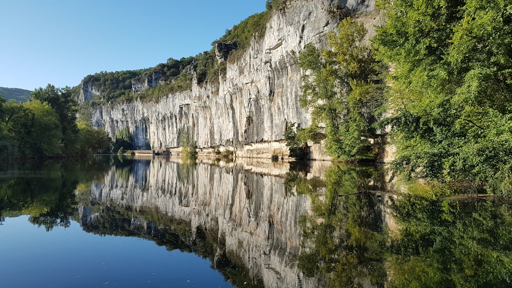 Montaña rocosa gris al lado del cuerpo de agua durante el día