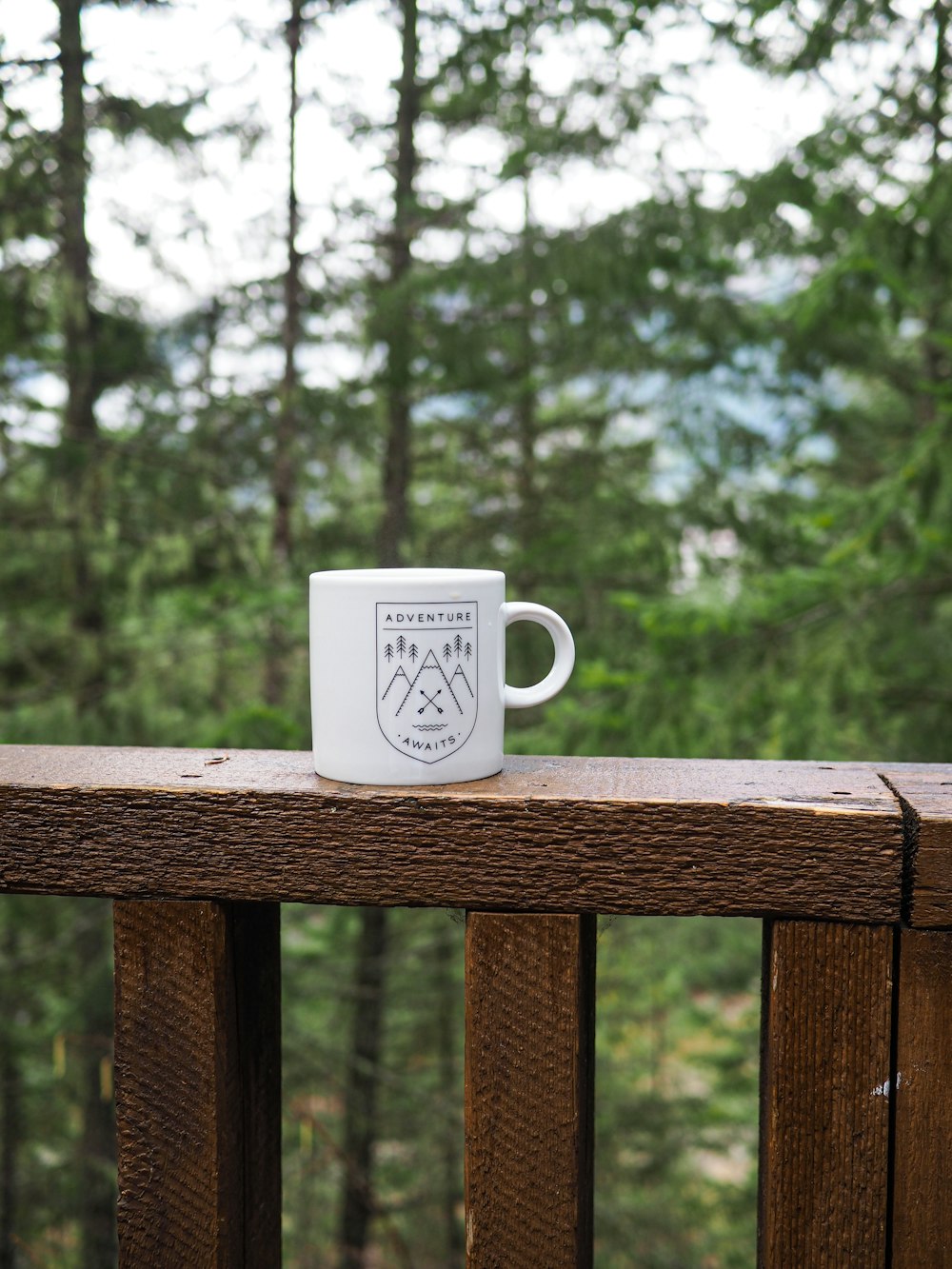 white ceramic mug on brown wooden fence