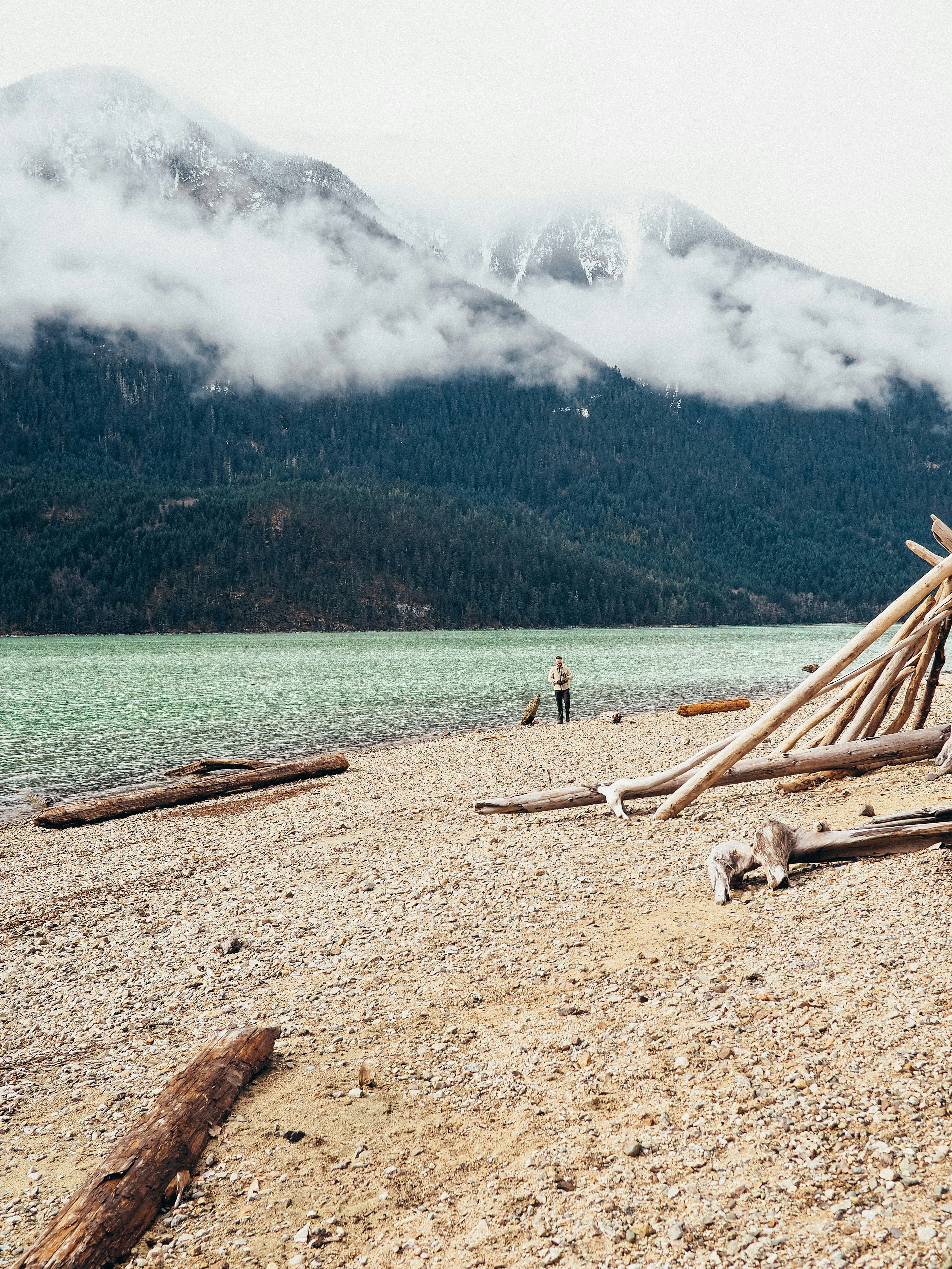 person in white shirt standing on brown sand near body of water during daytime