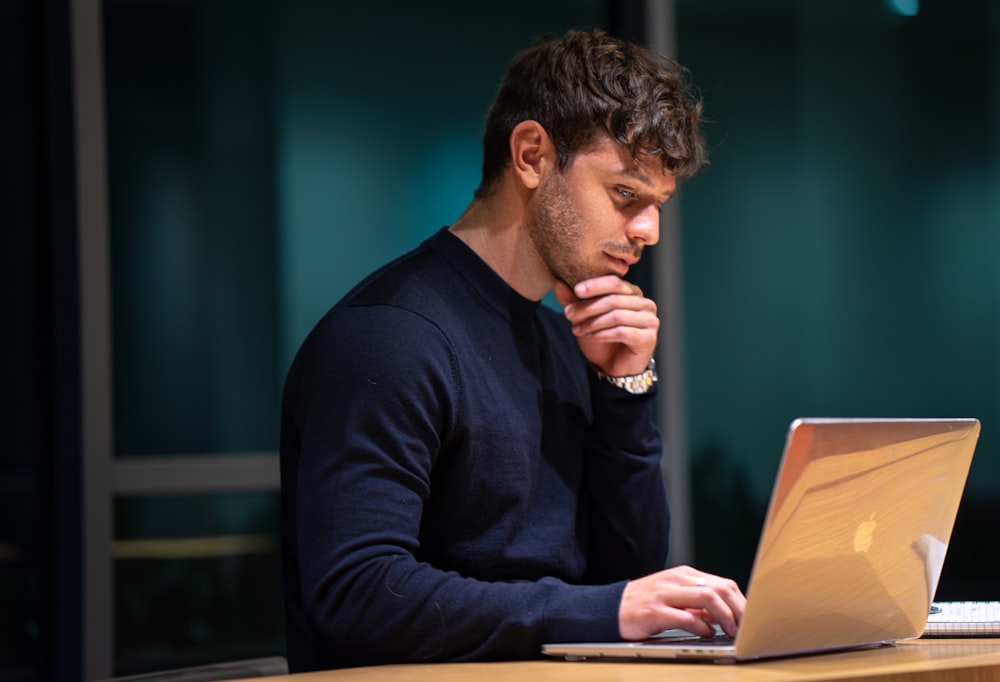 homem na camisa preta de manga comprida sentado na frente do macbook