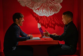 A mentor and student engaged in a lively discussion in a bright office setting.
