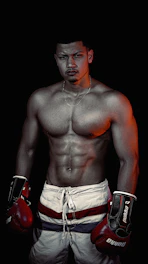 Moody studio shot of a muscular man lacing up his training gloves, surrounded by dark fitness gear.