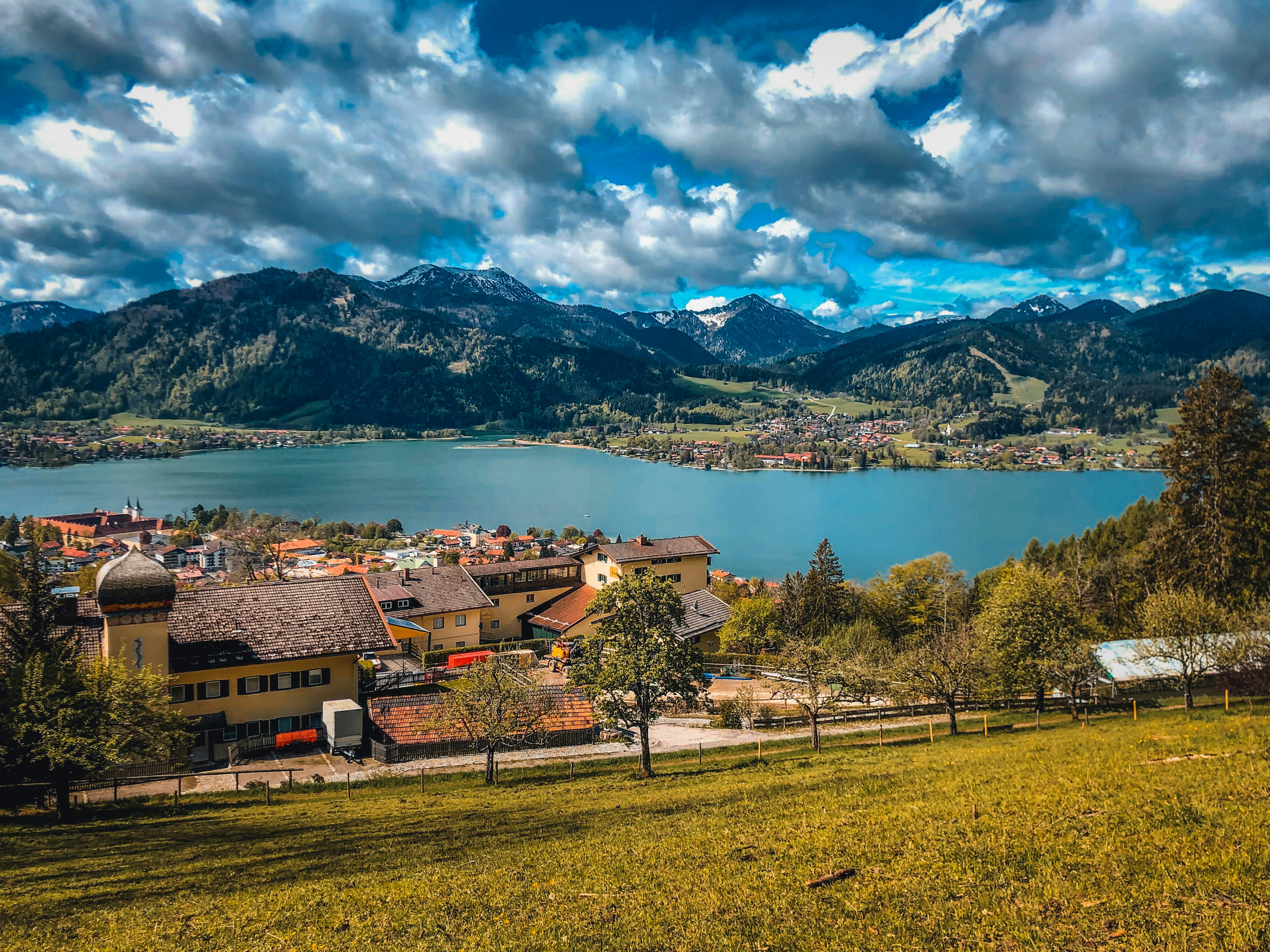 Maison brune et blanche près du lac sous le ciel bleu et les nuages blancs pendant la journée