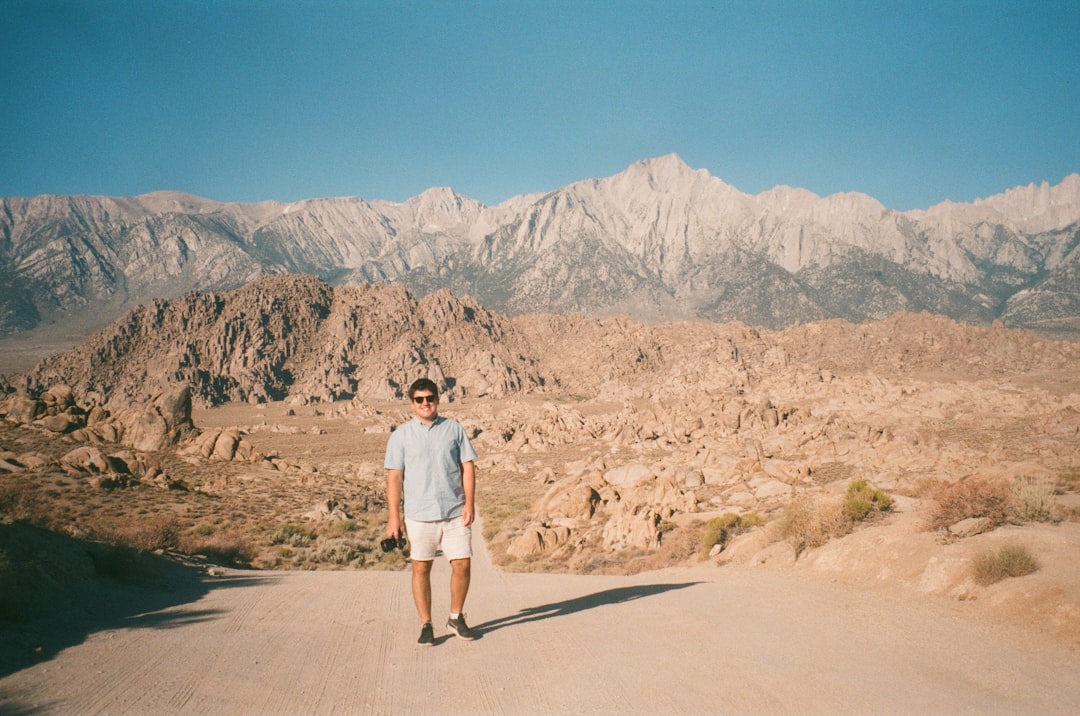 man in white t-shirt standing on gray asphalt road during daytime