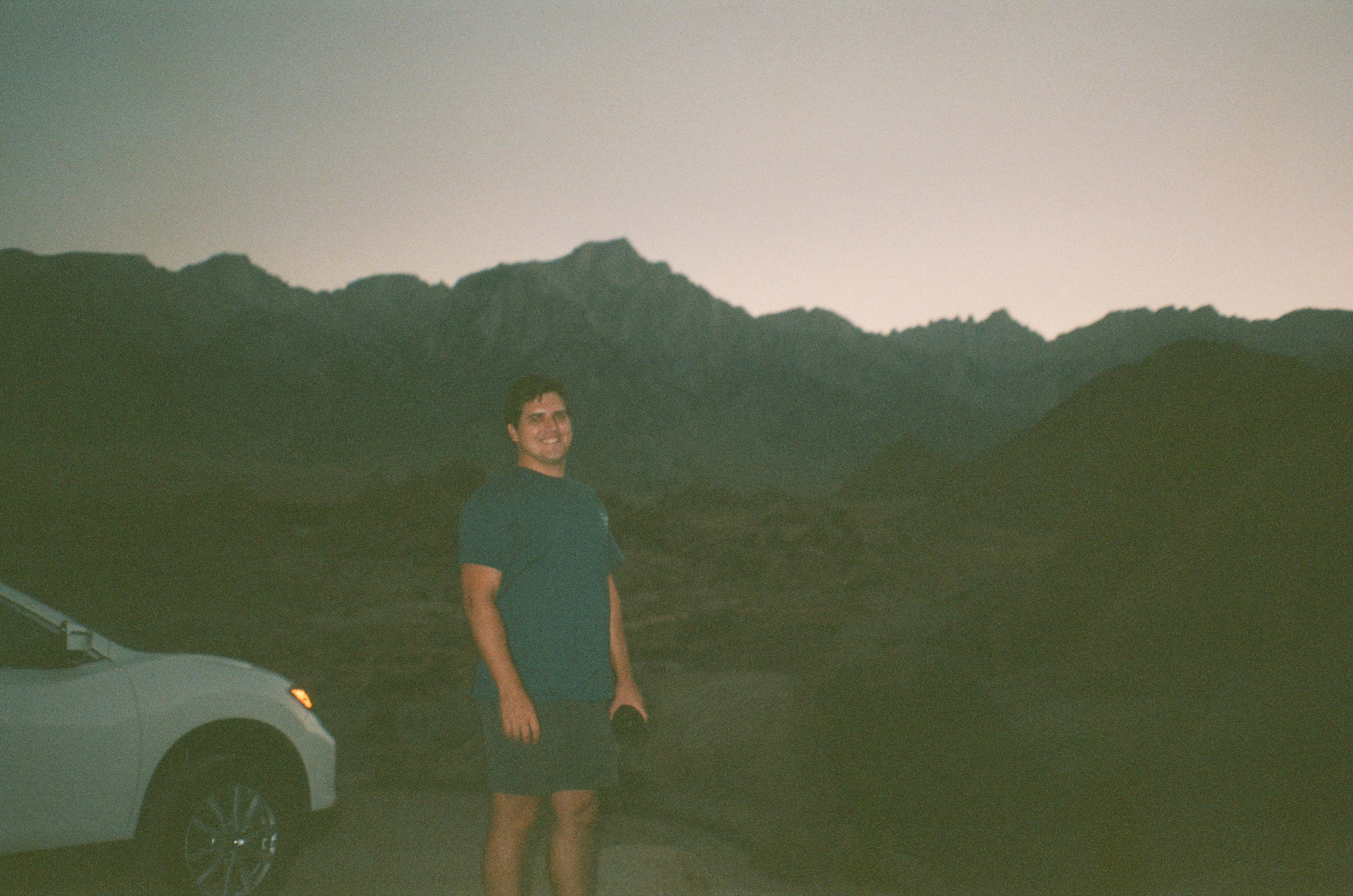 man in black polo shirt standing beside white car