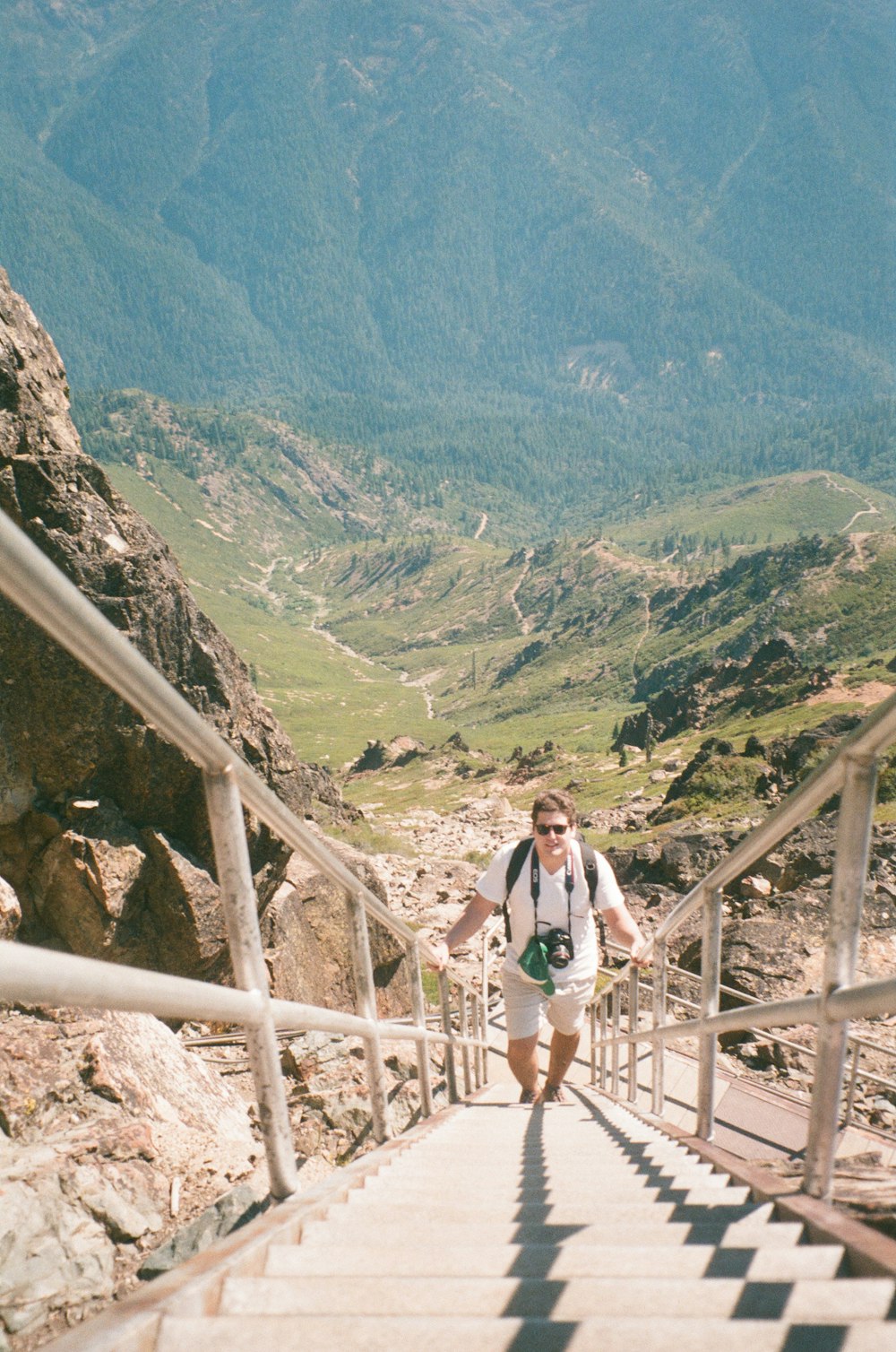 woman in white shirt and black shorts standing on brown wooden bridge during daytime