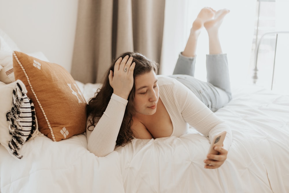 woman in white long sleeve shirt lying on bed