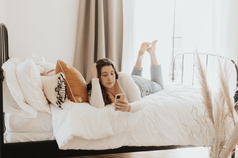 woman in white long sleeve shirt lying on bed