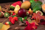Seasonal fruits arranged artistically on a rustic wooden table with splashes of juice and natural leaf graphics.
