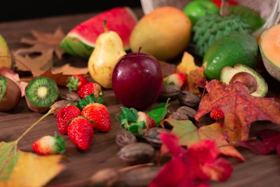 Seasonal fruits arranged artistically on a rustic wooden table with splashes of juice and natural leaf graphics.